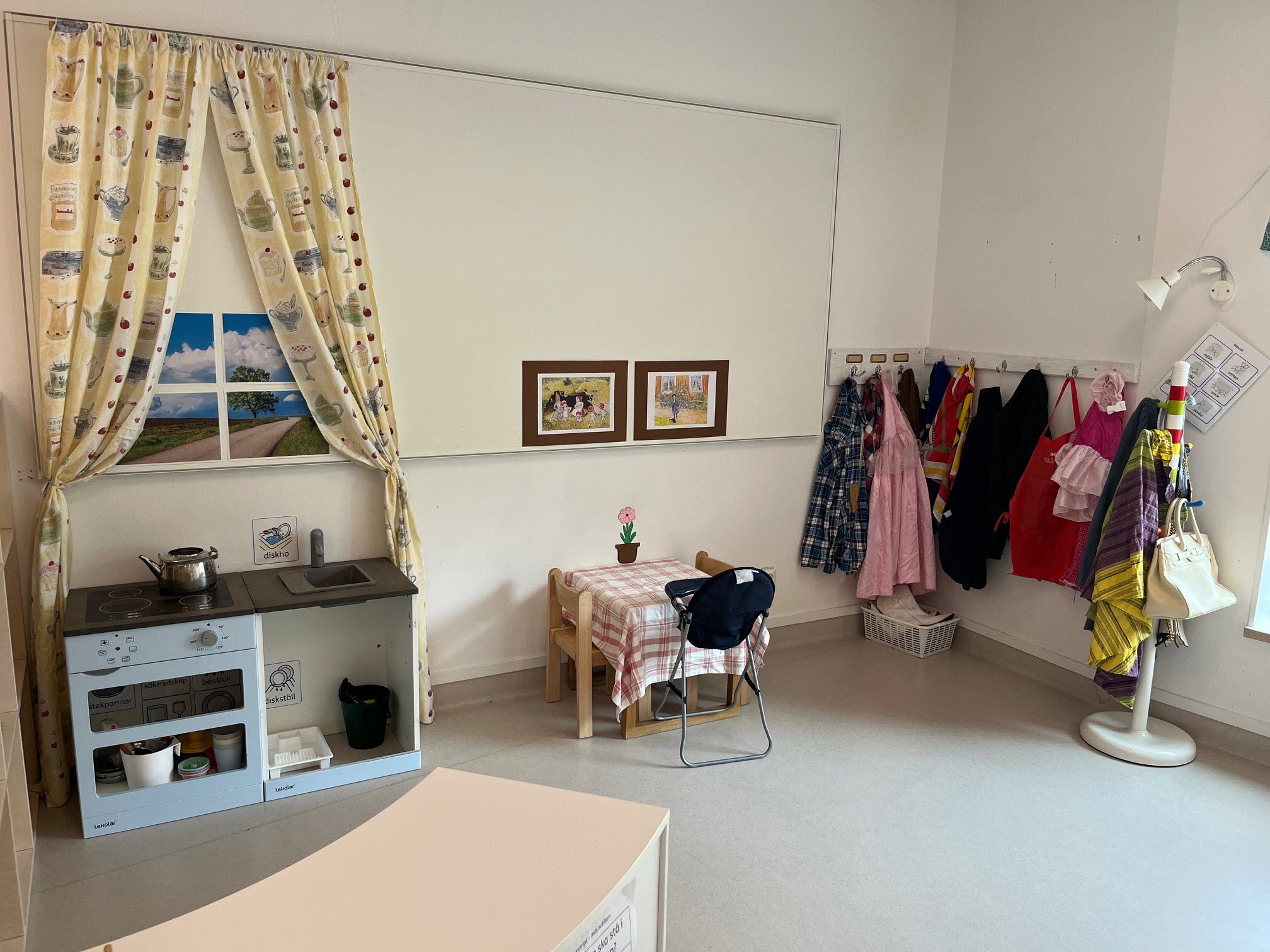 Temarum med kläder för teater, leksakskök och bord för lek.