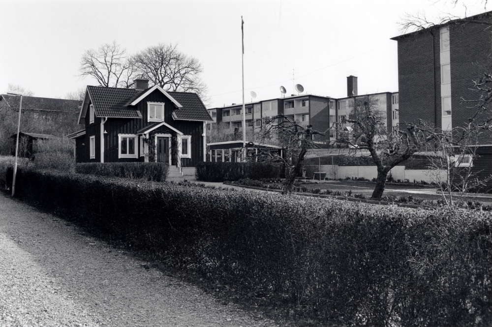 Ett hus som får vara kvar vid rivningen av de s k Trädgårdskvarteren vid Mörbyvägen.  Bostadshuset har adress Sommarvägen 5 och är bostad för familjen Gunnar Karlsson.  I bakgrunden syns HSB:s flerfamiljshus vid Mörbyvägen.  T h skymtar flerfamiljshus med adress Fornminnesvägen