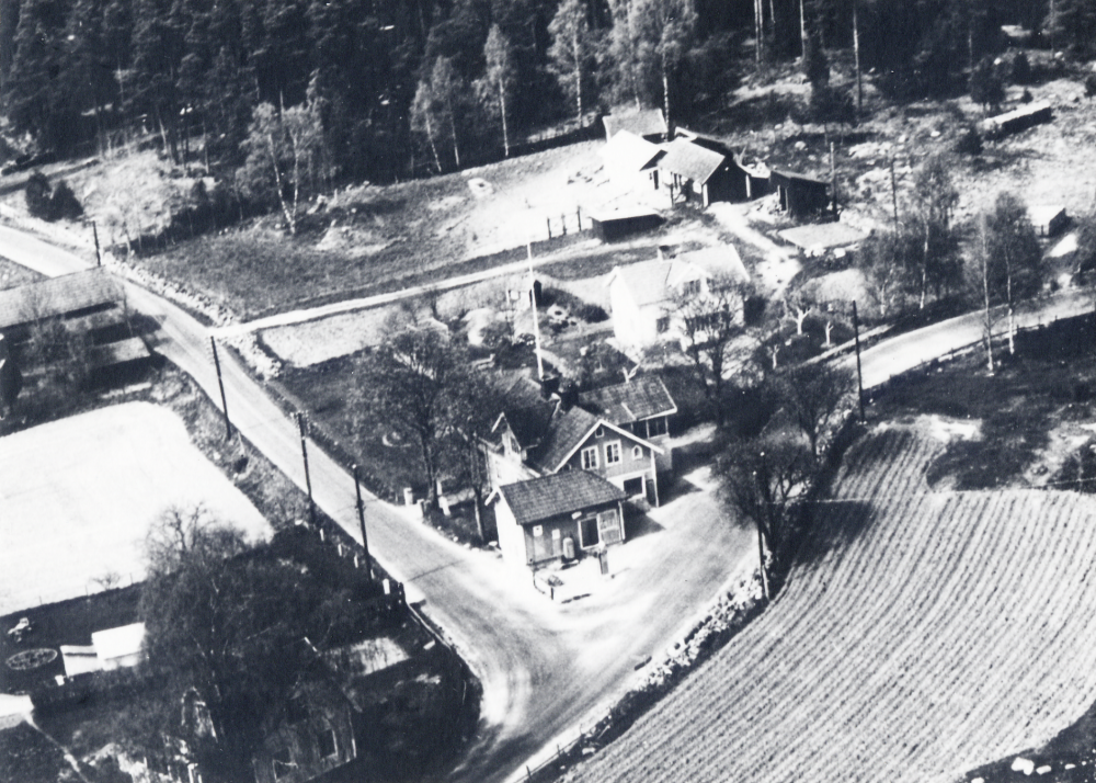 Flygfoto  över  Karlbergs affär  som låg i korsningen mellan vägarna till Kårsta och Gottröra. Den uppfördes 1888 av  Severin Carlsson.  Sista innehavaren var  Sigvard Jansson  som ännu 1989 använder huset som sin bostad.    
Se Lanthandlare i vallentunasocknarna vid Roslagsbanan