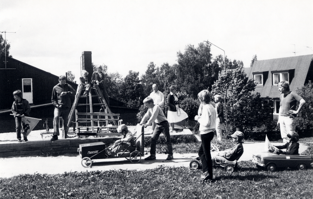 Lådbilstävling  i  Villaföreningen Ekliden  i  Bällsta  Fr v  Magnus Hillbo  starter,  Gunnar Hillbo  tidtagare, i klätterställningen  Per Lagergren  och  Roland ?   Jan Steiner   Mats Olsson   Gösta Heidmark   Birgitta Heidmark   Robert Heidmark  skymd  Staffan Lagergren   Kaia Levenius   Mikael Hillbo   Roberto Dünkelberg  och sittande i sista bilen  Rani Dünkelberg