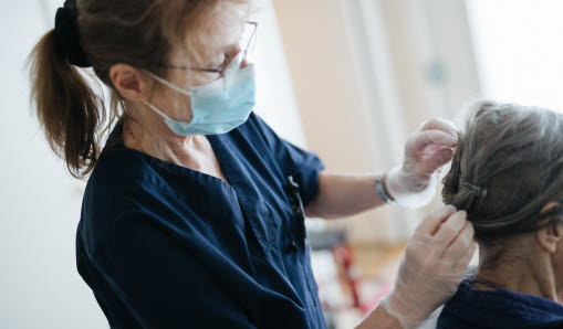 Hemtjänstmedarbetare fixar med kundens hår