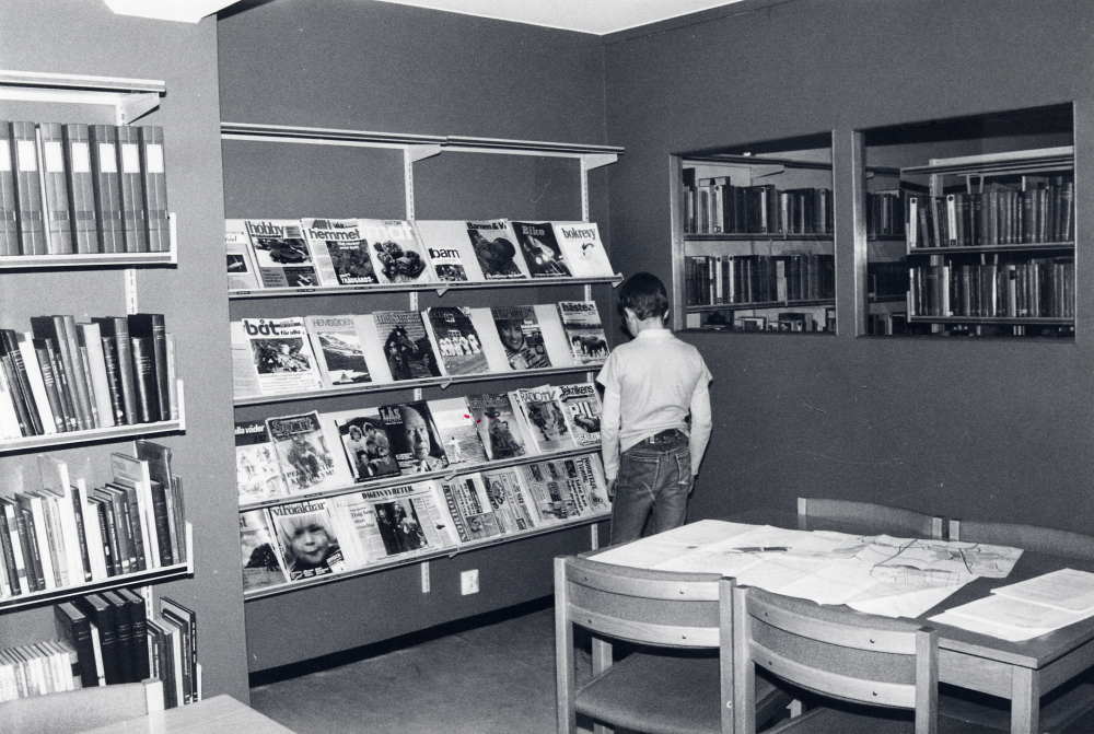 Interiör från Karby bibliotek, Tallstigen.  Mikael Hillbo tittar på tidskrifterna i tidskriftshörnan i läsrummet