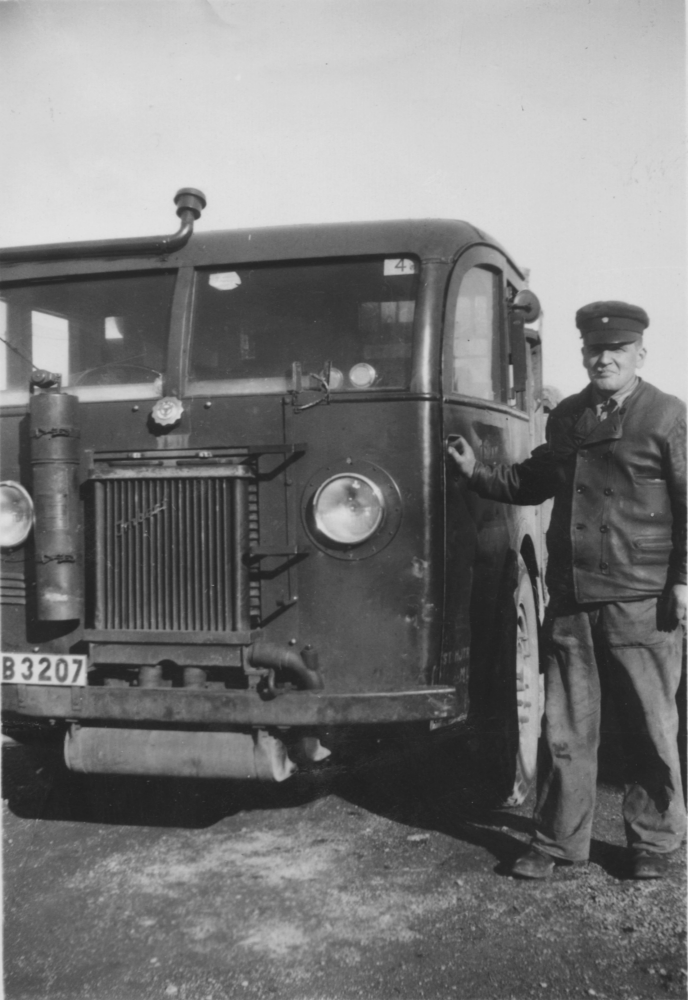 Martin Karlsson, en av Roslagsbanans lastbilsstations förare, bredvid en av lastbilarna som användes för att transportera mjölk. Roslagsbanans lastbilsstation hade sin bas i Markim dock är det inte säkert att bilden är tagen i Markim.
Bilden kommer från Lunda hembygdsförening