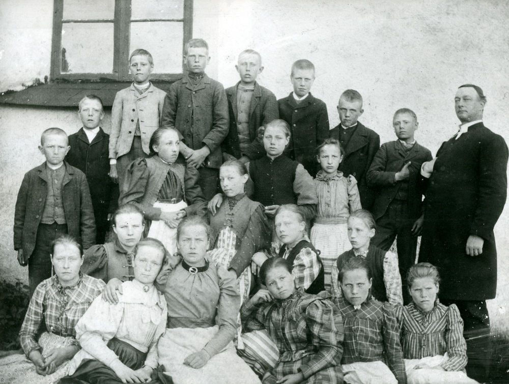 Konfirmander/skolbarn med okänd prost utanför okänd kyrka
Pojken längst t h med handen innanför rocken, precis som prästen, heter Johan August Johansson och blev senare far till barnen Artur, Asthild och Anton Johansson, Össeby-Garn