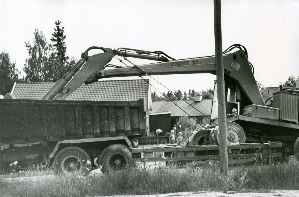 Tung trafik passerar mellan lekplats och villor i Brottby.
•Fotografiet ingår i bildserien ”Vardagsliv i Vallentuna kommun” av Rachael Gough-Azmier & Gunilla Blomé, Haga Studios HB.