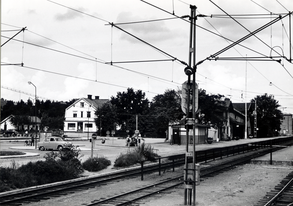 Vallentuna stationssamhälle med Vallentuna järnvägsstation t h och Tibells affär i bildens mitt. Framför stationshuset ligger Pressbyråkiosken Allra längst t h syns en matarstation till järnvägens elektricitet, senare riven