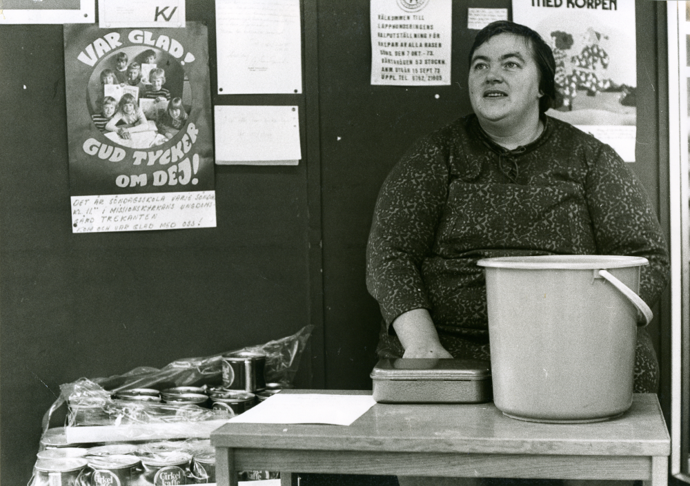 Vivianne Berg säljer lotter i Konsums entré. Vivianne Berg föddes i Jämtland.
•Fotografiet ingår i bildserien ”Vardagsliv i Vallentuna kommun” av Rachael Gough-Azmier & Gunilla Blomé, Haga Studios HB.