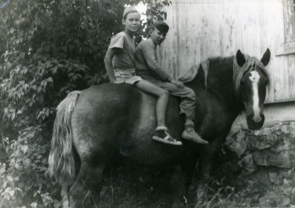 Timo Ekholm och Sami Suomalainen,  Sami Suomalainen längst bak och Timo Ekholm på hästen Stina vid Norra flygeln ”Lyan” vid Ekskogens gård. 

Timo och hans lillebror Sami kom till Sverige som finska krigsbarn 1944. Timo adopterades senare av ägarparet på Ekskogens gård i Kårsta, Inez och Manfred Ekholm. Läs mer i Timo Ekholms bok Krigsbarn 40.
