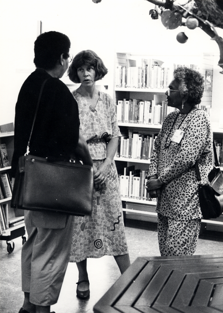 IFLA, International federation of library associations, har förlagt sin konferens i Stockholm 1990.  Bland förslag till utflykt fanns en rundtur i Vallentuna med besök på Vallentuna bibliotek och vikingalunch på Stora Benhamra. Lena Lundgren, guide m m, samtalar med två av deltagarna vid trädet i barnavdelningen i samband med visningen av bibliotekets lokaler