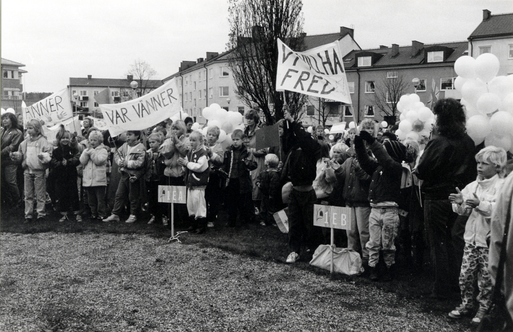 Barn från Ekebyskolan har tågat till Kommunalhusparken på FN-dagen 24 oktober. Här står de i parken med sina banderoller och stora knippen med vita ballonger som de skall släppa upp i luften för fred i världen