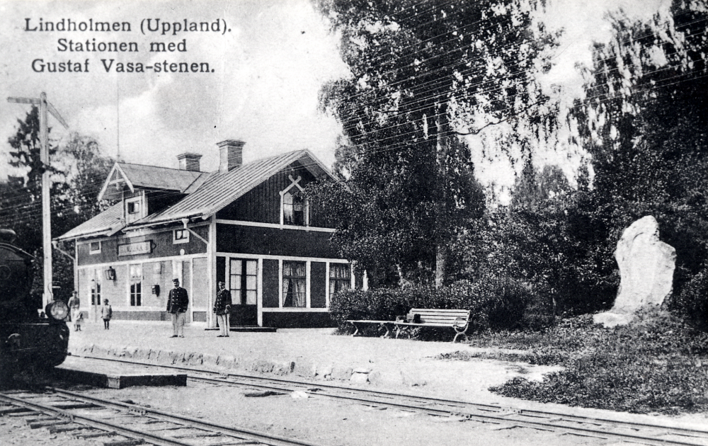 På perrongen står ev stationsinspektor Henrik Oppermann . Till sommaruniform hörde egentligen ljus kavaj och mössa. Bilden är tagen före 1920, då byggdes stationshuseet om. Längst till vänster skymtar ett ånglok Till höger syns Gustav Vasa-stenen