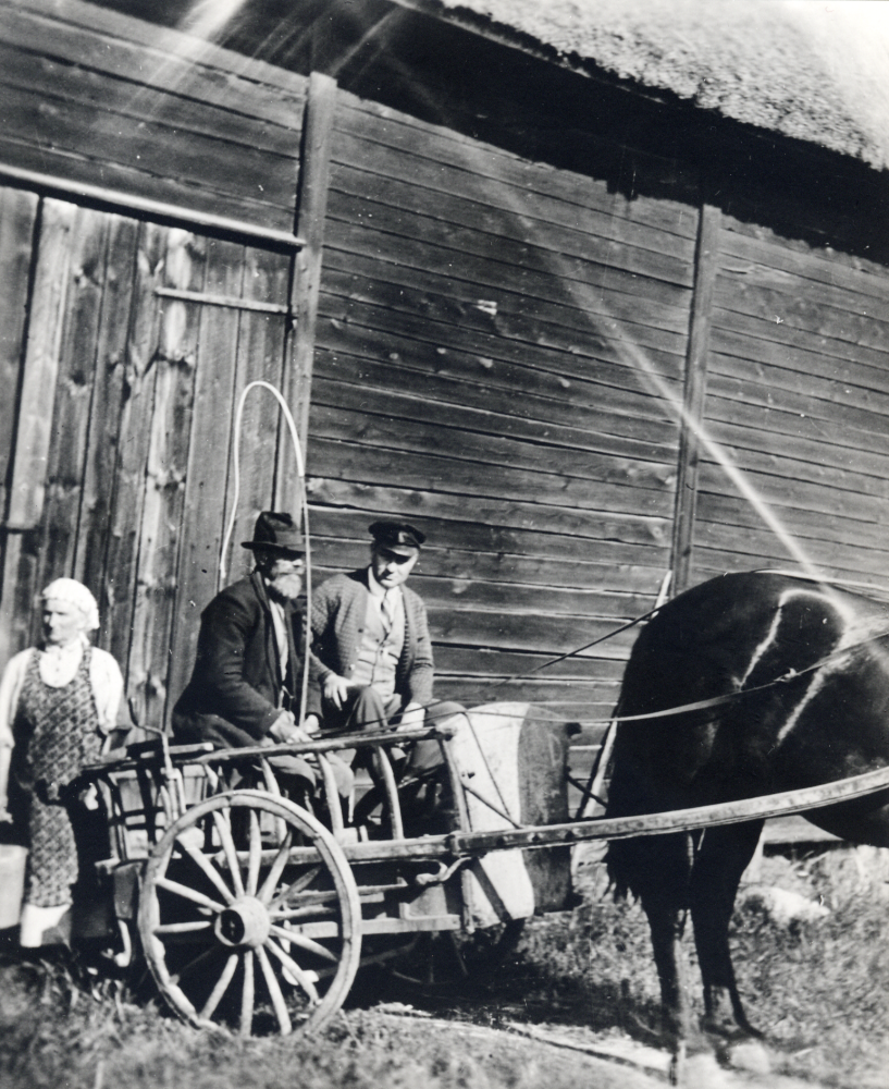 Augusta Gustavsson  med hink i handen och  Robert Gustavsson  sitter t v i den tvåhjuliga  vagnen  dragen av en  häst
