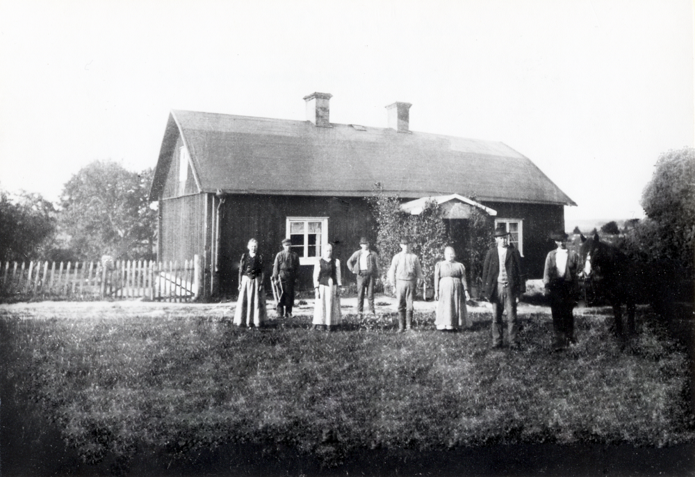 Johanna Östervall står i bildens mitt tillsammans med sönerna t h Fritz Östervall och Carl Östervall med hästen. Femte mannen från vänster är troligen Birger Östervall. Tjänstefolket står t v. Östervall var de sista brukarna av Rickeby gård. Marken köptes av AB Billiga tomter omkring år 1910.