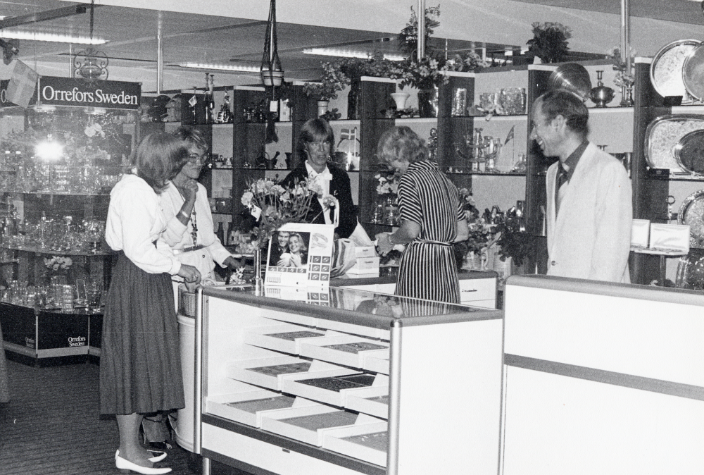 Torghuset invigs 26 augusti 1982.  Konsumhuset har byggts om för flera olika små affärslokaler och fått namnet Torghuset.  Här syns Rimbes, med glas, porslin, smycken och presentartiklar. På bilden samtalar fr v okänd, Marianne Ahrneteg, ??, Ulla Andersson och Bruno Rimbe