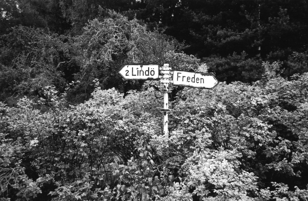 Vägskylt på Tallhammarsvägen vid avfarten till gamla vägen före Västlunda.  Skylten har text t v 2 Lindö och Freden utan avståndsangivelse