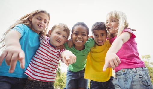 Fem barn som håller om varandra och tittar neråt mot kameran.