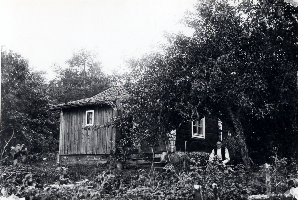 Hagstalund i Frösunda. I trädgården sitter Klara Ek.  Hon var hushållerska hos "gubben" Sjögren, en s k klok gubbe som var till stor hjälp för frösundaborna när folk och fä var sjuka.  När Sjögren dog tog Klara Ek över verksamheten i Hagsta eller som stället också kallades, Hagstalund