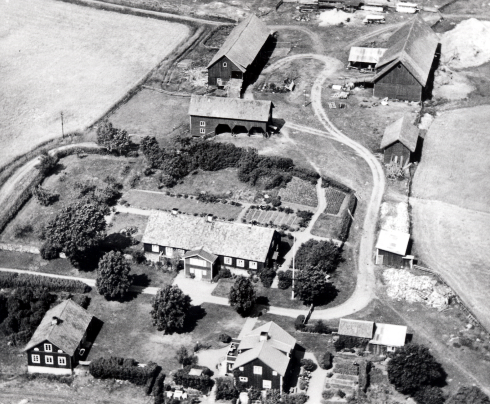 Flygfoto över Helgö gård med huvudbyggnad, flyglar och ekonomibyggnader.  Mangårdsbyggnaden med anor från 1700-talet brann ner till grunden 1960
