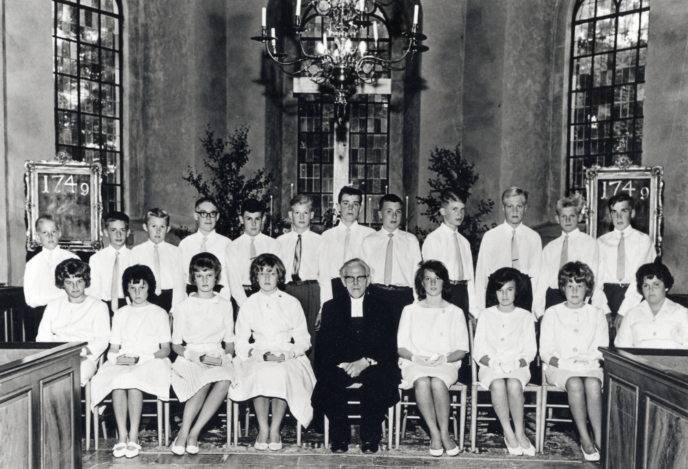 Konfirmation i Vallentuna kyrka. Kontraktsprost Sven Vängby tillsammans med sina konfirmander i koret. Bakre raden fr v okänd, Åke Holmberg, Johan Rosenlund, Lars Berger, okänd, Olof Johansson, ? Larsson, okänd, Herman Berggren, okänd, okänd och Kjell Karlsson.  I nedre raden är nr 3 fr h Eva Gustavsson