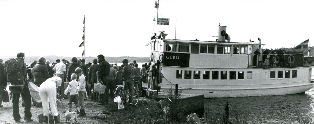 Össeby hembygdsförening firar tioårsjubileum den 25:e augusti 1980 med ångbåten Gurli som tidigare trafikerat Åkers kanal.
2021-02-22 nya uppgifter: Gurli, före detta Åkers kanal, vid Österskärs brygga när Össeby hembygdsförening gör en utflykt till Ängsö för att känna historiens vingslag på det gamla fartyget.