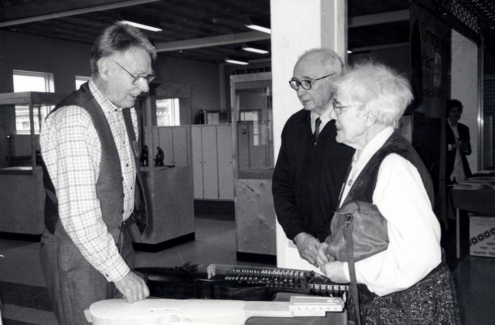 Stockholms läns hembygdsförbund har årsmöte och firar samtidigt 25-års jubileum i Vallentuna gymnasium.  Vallentuna hembygdsförening och Vallentuna kulturförvaltning  är värdar med utställningar och program.  Här besöker Gertrud och Yngve Gustavsson från Markim bordet där Torvald Nordman visar tillverkning av nyckelharpor