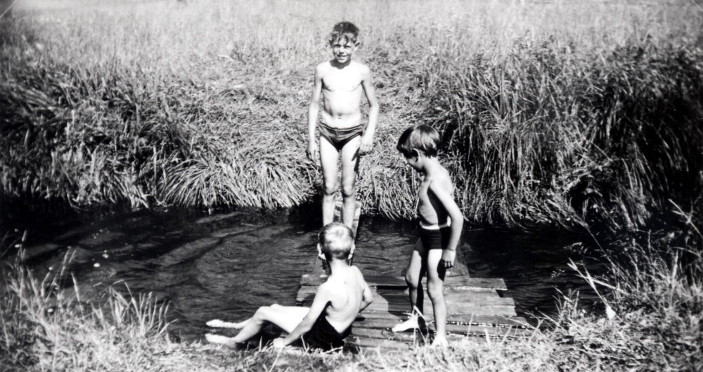 Pojkarna Robert Höglund, Timo Ekholm och Ulf Tholsjö badar i Lillån vid "Stjärnbergs" nedanför Ekskogens gård.  Badplatsen kallades Stjärnbergs trädgårdsmästaren Stjärnberg som bodde intill.  

Timo och hans lillebror Sami kom till Sverige som finska krigsbarn 1944. Timo adopterades senare av ägarparet på Ekskogens gård i Kårsta, Inez och Manfred Ekholm. Läs mer i Timo Ekholms bok Krigsbarn 40.