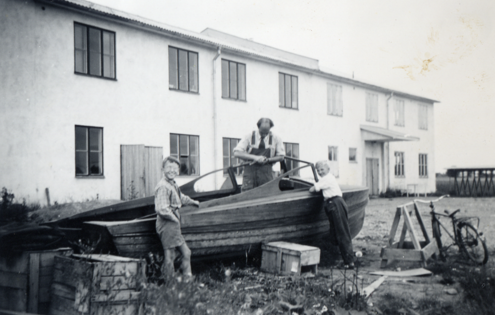 Johansson arbetar med en båt, som står uppställd utanför Vallentuna möbelindustri.  Bo Persson står t v, han bor granne på Banvägen 25.  Den andra pojken är okänd