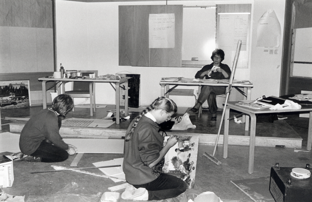 Förberedelser inför Människan och hästen – en utställning i Vallentunasalen 26 januari – 15 mars 1993 av Eva Rahmqvist i samarbete med föreningar i Vallentuna och kulturförvaltningarna i Danderyd, Täby, Djursholm och Tyresö.  Utställningen visar hästens utveckling i människans närhet och tjänst.  Fr v Ellen Hahn från Tyresö kulturförvaltning, praktikanten ???? och vid bordet sitter Eva Rahmqvist