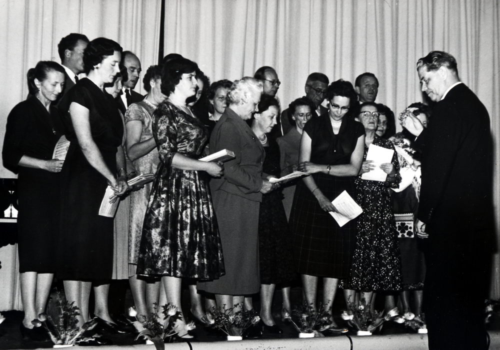 Vallentuna hembygdskör  under ledning av  Josef Andersson  sjunger vid en konsert i  Hjälmstaskolans aula. Elsa Nordin står längst till vänster