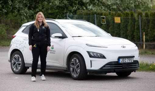 Porträtt av Thea, med hemtjänstbil framför Kvarnen i Vallentuna