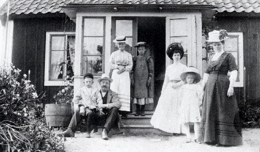 En grupp människor framför en stuga på 1910-talet