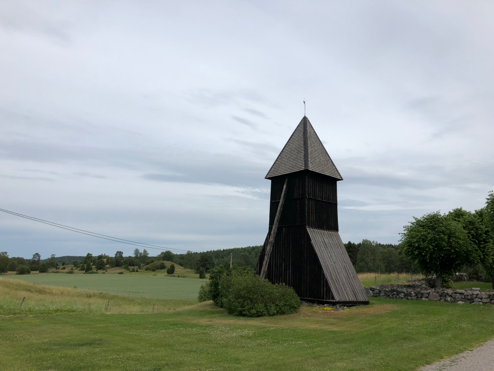 Vada kyrkas klockstapel med Vada sjökullar i bakgrunden.