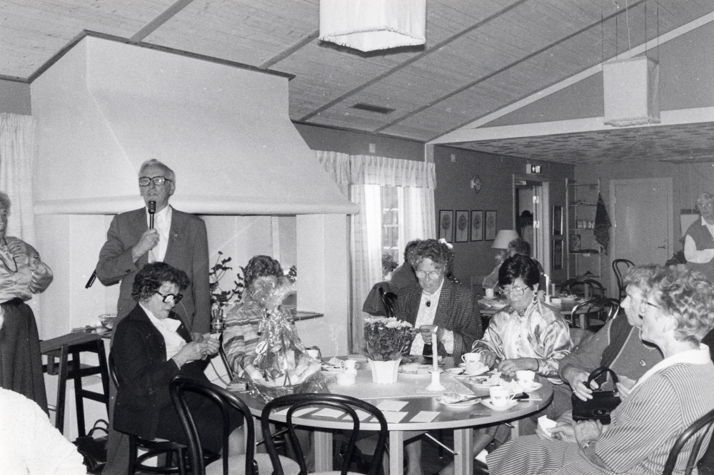 Välklädda veteraner. Pensionärsföreningen KOM har modevisning i Mathiasgården. Affärerna Ceci, Mamsell Kerstin, Björns herrmode och Rosita parfym och present visar kläder. Medlemmarna är själva mannekänger. Biljettpris 25 kr inklusive kaffe/te och smörgåsar. Sven Skoog vid mikrofonen vid lottdragning efter visningen. Vid bordet fr v nr 2 Rut Noreen nr 3 Ingebill Nilsson