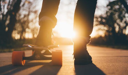 Två fötter i motljus, den ena står på en skateboard