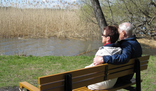 En man och en kvinna sitter på en bänk vid vattnet