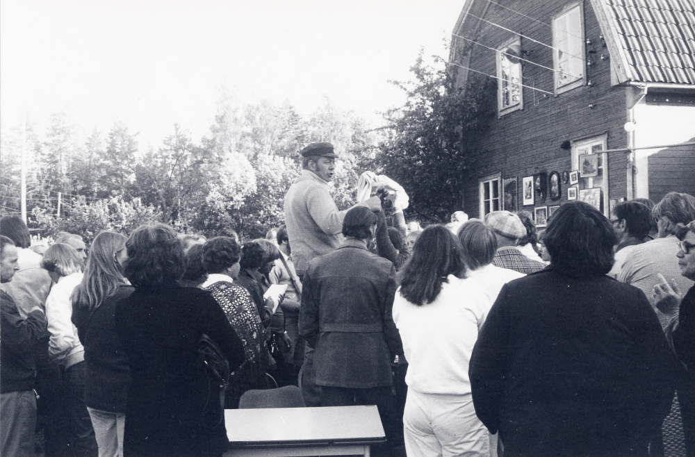 Sten Zetterlund  håller  auktion  på  Karlavägen 8.  Här står han iklädd vegamössa och ropar ut sina varor. Tidigare hade Zetterlund sin auktionsfirma i  Åbyholms gård.  Huset på Karlavägen revs 1989 när bostadsområdet Hagaberg byggdes