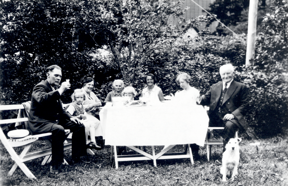 Kaffekalas i trädgården vid Karlborg Fr v Edvard Johansson dottern Gunnel Johansson hustrun Signe Johansson Augusta 'Nanna' Lundin Edvards och Signes son Thord Johansson tog senare namnet Tordmar, obekant släkting, Rut Axén släkting morbror till Signe och hunden Mitzi Nanna Lundin hade från början Karlborgs handelsbod mittemot Angarns kyrka. Edvard och Signe Johansson arrenderade handelsboden från 1918 till 1938, då Edvard dog. Signe drev sedan affärsrörelsen ensam fram till 1948