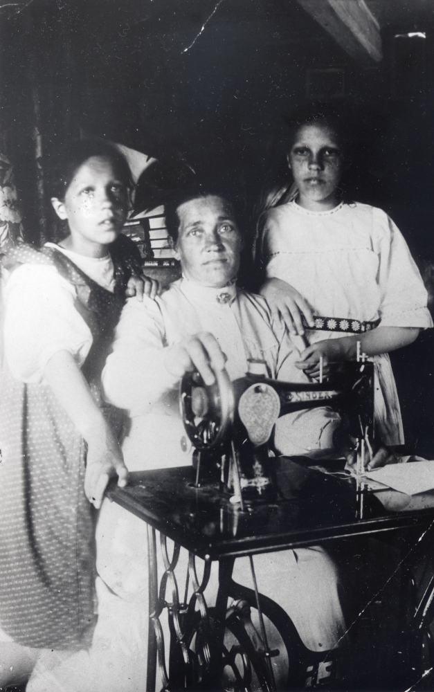 Maria Widén med döttrarna Judit t v och Agnes vid symaskinen i Sjöberg, Frösunda.  Symaskinen Singer var oumbärlig i hushållet, på den syddes och lappades alla kläder.  Axel och Maria Widén bodde i Sjöbergstorpet 1910-1915