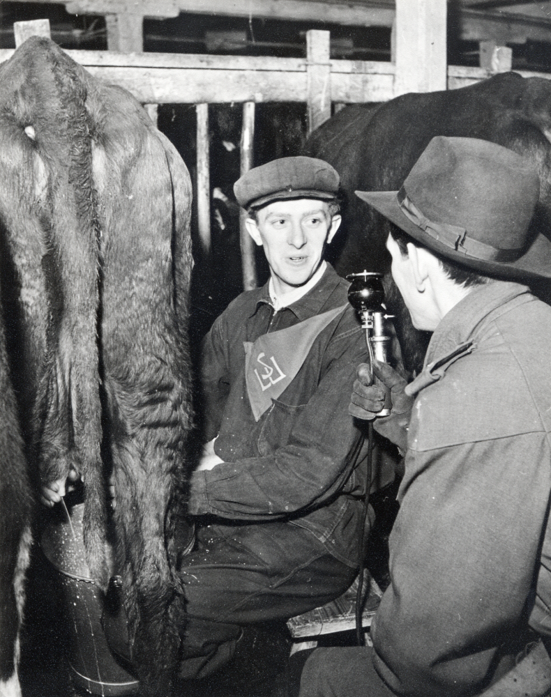 Edgar Axzell från Ekskogen i mjölkningstävlan anordnad av SLU, Svenska landsbygdens ungdomsförbund, på Brottby gård i Össeby-Garn.  Medan Edgar Axzell mjölkar, blir han intervjuad av Bo Teddy Ladberg, Sveriges Radio?.  Edgar kom nr 6  i tävlingen.