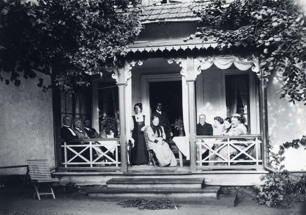 Össeby-Garns prästgård.  På verandan sitter bl a kyrkoherde Karl Hedén t h om dörren samt fru Ella på stolen i dörröppningen
