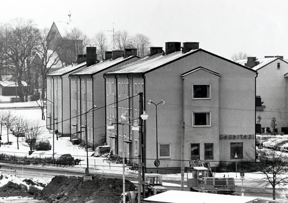 Centralvägen  med bostads- och affärshus. I bakgrunden  Vallentuna kyrka  I förgrunden t v pågår schaktningsarbete för vatten och avlopp inför byggstart av Tunahuset