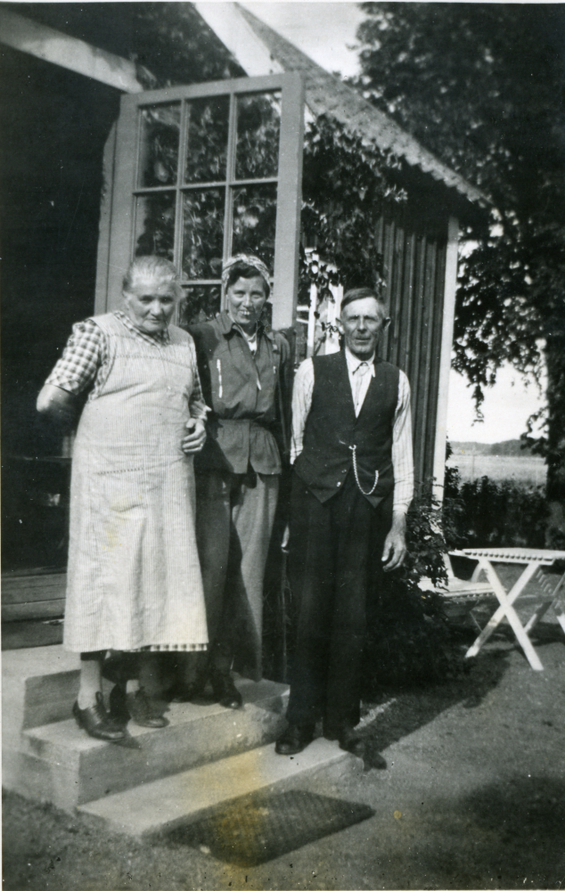 Till höger Viktor Emanuel Holm född 1875-11-27, Markims lantbrevbärare och kyrkvaktmästare, med hustrun Emma Vilhelmina Holm född Kvist 1874-07-07 till vänster, vid Klockargården. Eventuellt är det Sigri O i mitten. 

Folkräkning 1910, var familjen boende i Torpet Nydal, Markim: 
Holm, Viktor Emanuel, f. 1875 i Skånela Stockholms län, Torpare
Qvist, Emma Vilhelmina, f. 1874 i Markim Stockholms län
Sönerna: Birger Emanuel, f. 1901 i Danderyd Stockholms län
Gustaf Evert, f. 1903 i Markim Stockholms län
Johan Herbert, f. 1904 i Markim Stockholms län

