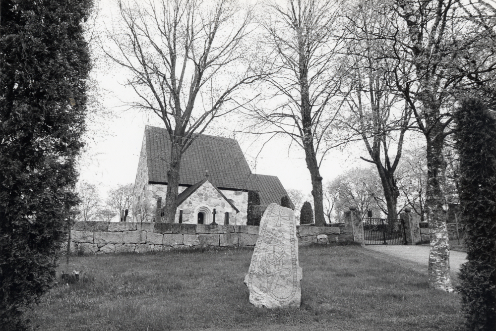 Össeby-Garns kyrka med en runsten utanför kyrkogårdsmuren
