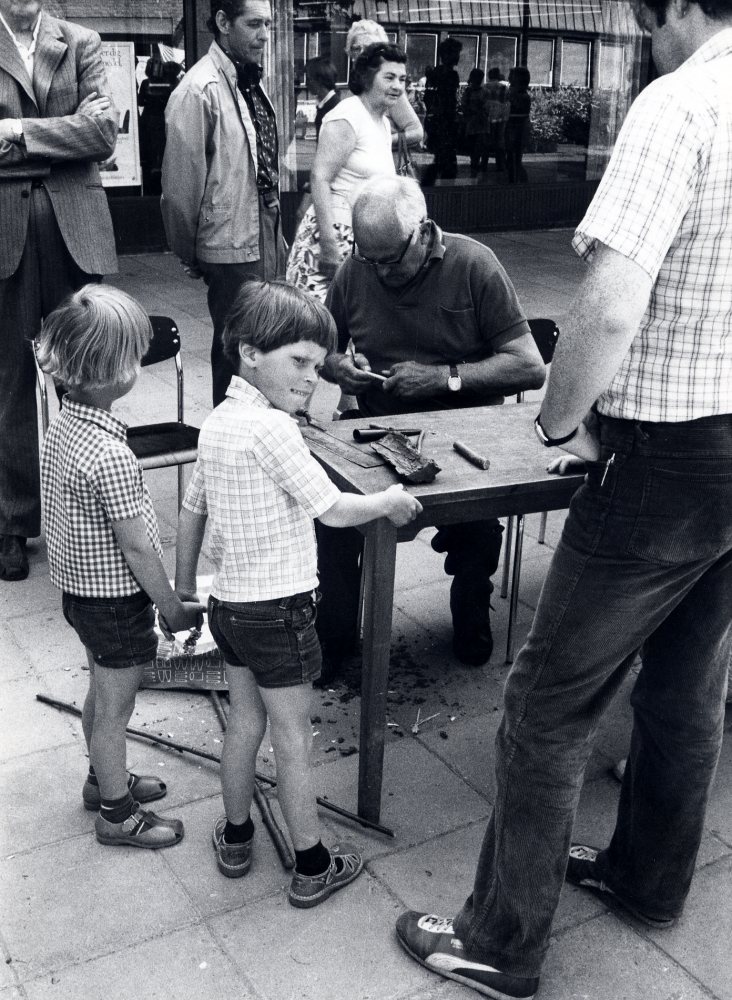 Vallentuna folkdansförening visar olika aktiviteter med tema Musik, slöjd och dans på Tuna torg. Här täljer Martin Linder barkbåtar medan bl a pojkarna Sven Lundgren tv och Mårten Lundgren tittar på