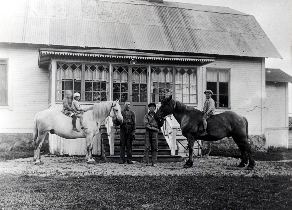 Rörby gård med fastighetsbeteckning 1:1, Nedre Rörby gård i Angarn.  Huvudbyggnaden byggdes på 1860-talet.  Framför huset håller två män  två  hästar, på den vita hästen rider två flickor, på den andra en pojke