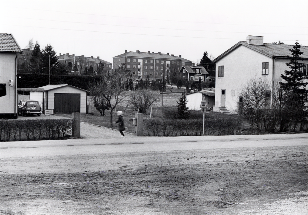 Villabebyggelse vid Banvägen i Vallentuna finns kvar 1967. På skylten vid grinden står "Parkering förbjuden".  T h Vallentuna biograf.  Flerfamiljshus vid Mörbyvägen syns mellan husen och en trävilla finns vid Vikingavägen. Nedanför den villan byggs senare Daghemmet Vikingen