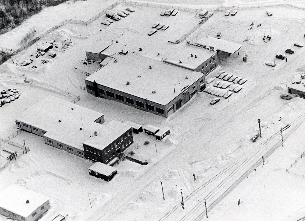 Flygfoto över Vallentuna industriområde. Fr v K S Karlssons smidesverkstad, Sme-Kalle, Vallentuna elverk och Vallentuna motor. Vägen framför byggnaderna är Industrivägen och spåren till Roslagsbanan t h.