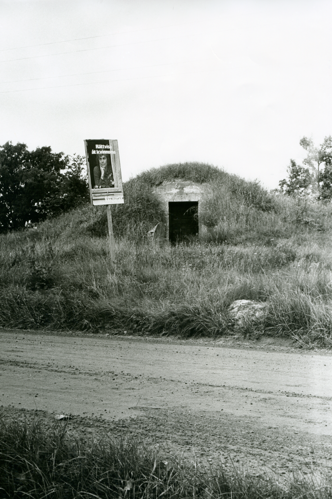 Valaffisch från Folkpartiet uppsatt mitt emot vallokalen i Kårsta skola. Budskapet är "Rättvisa åt kvinnorna". En jordkällare syns i bakgrunden.
•Fotografiet ingår i bildserien ”Vardagsliv i Vallentuna kommun” av Rachael Gough-Azmier & Gunilla Blomé, Haga Studios HB.