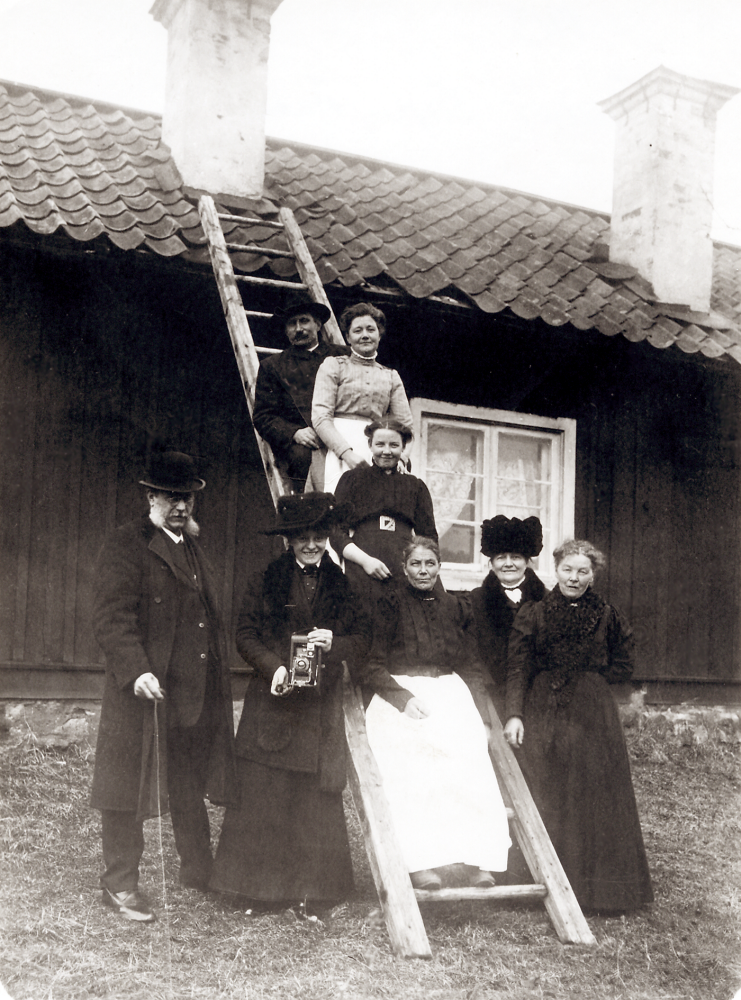 Väsby gård  Sofie Petterssons stuga. På stegen står  Karl Singman   Frida Singman   Astrid Lindberg  och längst ner  Ina Pettersson  Stående framför  Herr Forsell  dottern  Anna Forsell  hustrun  Anna Forsell  och  Sofie Pettersson