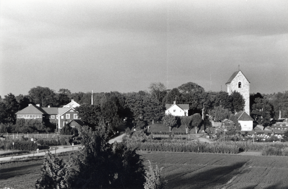 Vallentuna kyrka sedd från Väsby kvarn.  Byggnaderna fr v är Mathiasgården, Arrendatorsbostaden, Stefansgården och kyrkan